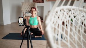 Online learning and live streaming concept. Woman blogger tells how to do aerobic exercise from fitness on phone camera. Athletic girl conducts training via video call. Online training course at home.