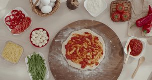 Woman making Italian pizza with arugula, putting tomato sause on raw dough for pizza. Culinary course recipe with steps how to cook.