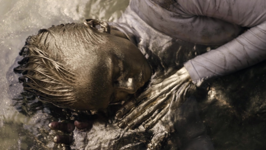 gold woman is floating in shallow with golden shiny dye, artistic shot of moving lady, body art performance