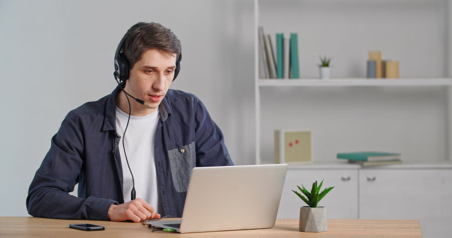 Caucasian millennial helpline operator advises client nods head approvingly, male online teacher leads video lesson remotely wears headphones supports student, businessman says yes in internet call Royalty-Free Stock Footage #1068736910