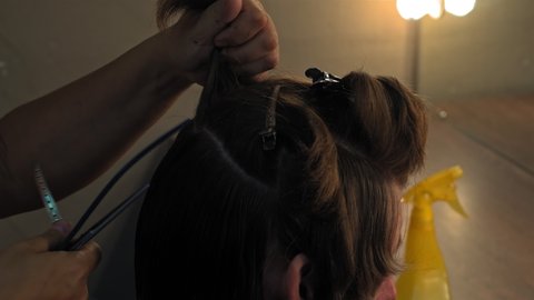 Close up back view hairdresser woman parts in sections mans head to trims back of his head pulling his hair cuts off the ends. High quality 4k resolution footage. 