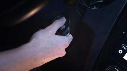 Close-up of a man starts the car. The driver turns the key in the ignition by hand. Car dashboard. The beginning of the journey. Man's hand with car keys. Igniting car.