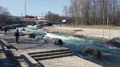 TACEN, SLOVENIA. 2.3.2020. Coach supervising canoe slalom athletes on training. Competitors training with kayak and canoe on fast river rapids 