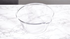 Time lapse. Step by step. Mixing ingredients for mini pancake cereal in a glass mixing bowl.