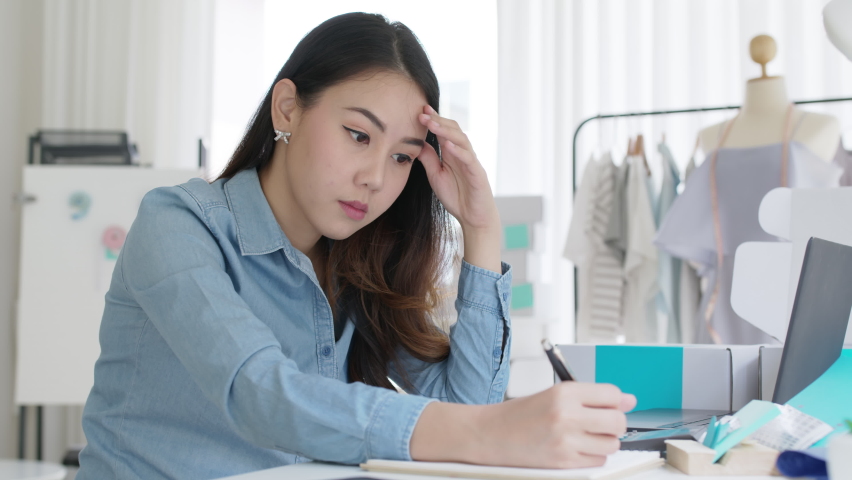 Young attractive asia female business owner thoughtful serious doubtful feel stress worry with financial problem in SME crisis small business challenges impact from covid coronavirus at home office. | Shutterstock HD Video #1068751727