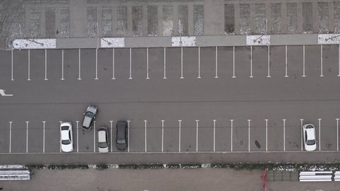 Cars leave parking spaces in the parking lot - top view Aerial shot. Cars leave an empty parking lot on a cloudy day during the quarantine coronavirus pandemic.