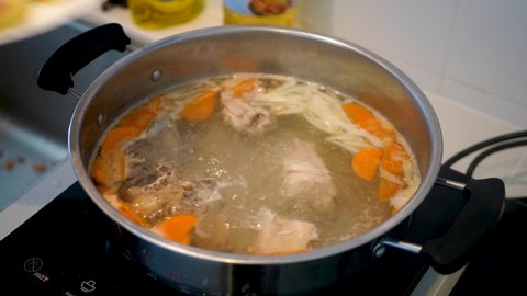 Housewife Prepares Food For Lunch For Family And Adds Potato To Chicken Soup. Stainless Saucepan On Electric Induction Cooker