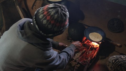 Indian Man in a rural village making Chapati inside his traditional village home . Chapati or roti is a traditional Indian bread made with stoneground whole meal flour, traditionally known as atta 