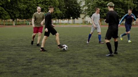 Soccer player gives a lob pass, cross to his teammate. Friends play football. Unexpected maneuver, deceptive movement. Amateur game in a small stadium. Workout training. Team match. Sport