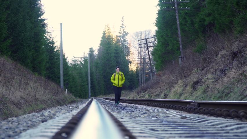 A woman with a backpack walks on the railway. Freedom and travel concept