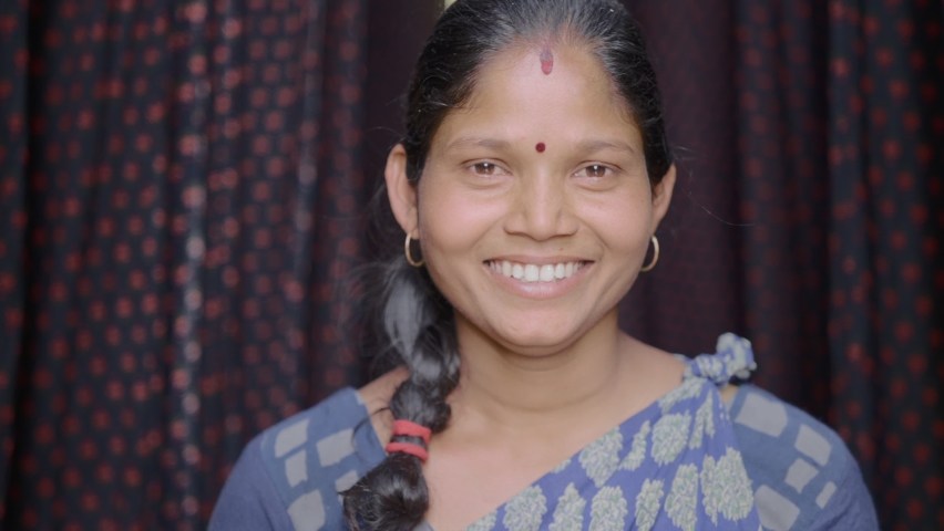 close up shot of an Indian female daily wage laborer of  local or domestic textile dyeing firm standing around the color printed cloth materials for the drying process smiling and looking at Camera Royalty-Free Stock Footage #1068763442