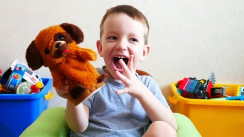 A happy little boy playing with a toy dog smiling and laughing