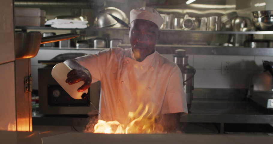 African american male chef frying in pan in restaurant kitchen. Working in a busy restaurant kitchen. Royalty-Free Stock Footage #1068767033