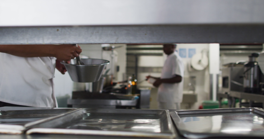 Midsection of diverse group of chefs preparing food in restaurant kitchen. Working in a busy restaurant kitchen. Royalty-Free Stock Footage #1068767435