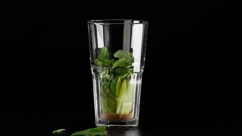 Steps in making Mojito cocktail by adding brown sugar, lime wedges and mint leaves into a tall glass