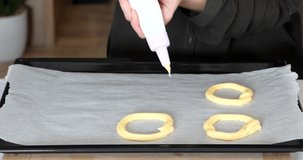 video of the process of making eclairs or choux pastries. woman lays out custard dough in a circle shape. High quality 4k footage