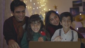Shot of Indian Asian cheerful and close-knit family sitting on a couch talking on an online video call using laptop with great excitement at home well decorated on the occasion of Christmas eve - Powered by Shutterstock - Get 15% off with code: PIKWIZARD15