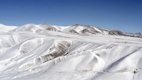 Drone video of mountains in winter. Beautiful landscape with peaks, slopes and cliffs of mountains covered with snow and ice. Aerial view Kazakhstan.