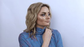 Beautiful young woman with bright evening make-up smoky eyes, freezes and wraps herself in a blue scarf. Girl model thoughtfully looks to the side on a white background. - Powered by Shutterstock - Get 15% off with code: PIKWIZARD15