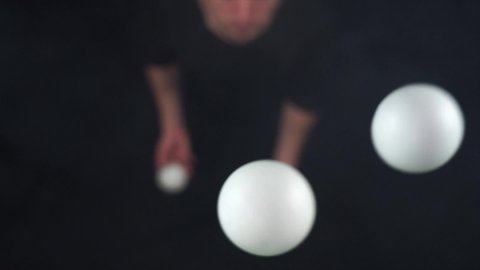 Circus artist wearing black juggling with white balls in slow motion