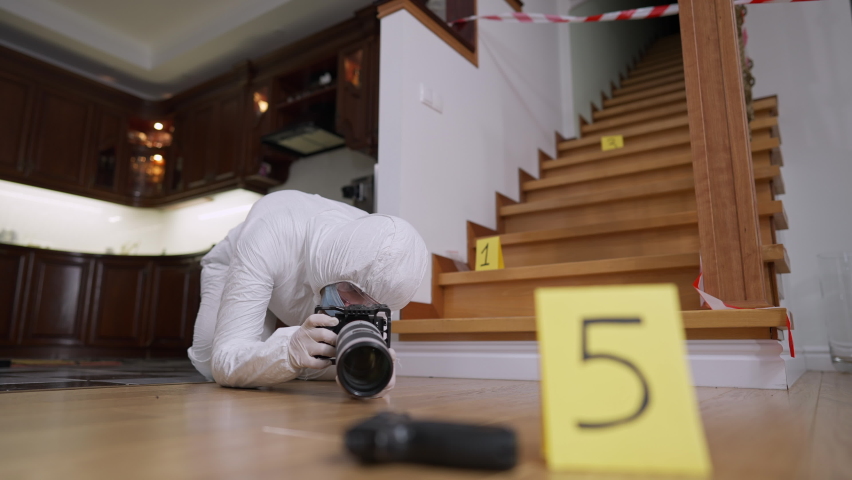 Wide shot of professional concentrated forensic scientist taking photos of clues at crime scene. Portrait of focused Caucasian woman in uniform photographing evidence of robbery or murder indoors. | Shutterstock HD Video #1068785006