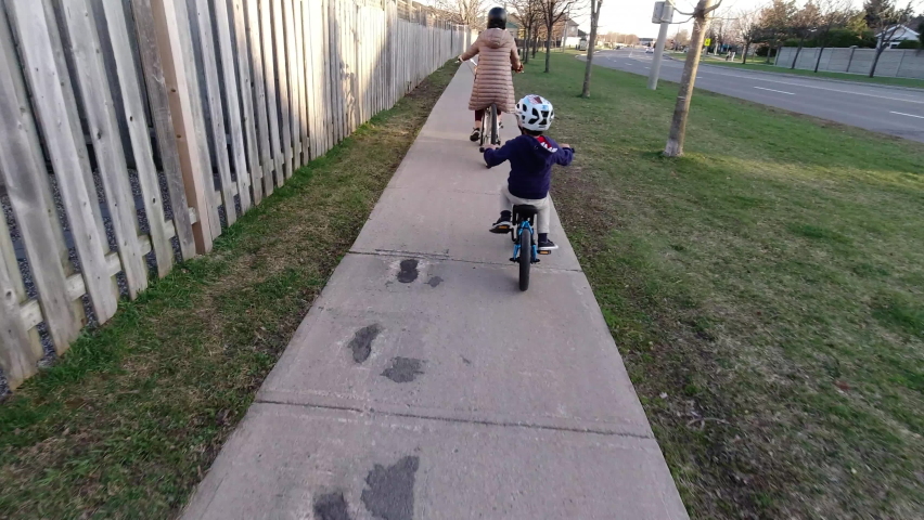 Young boy and mother go for a bike ride in spring - from behing tracking shot