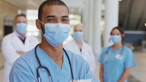 Confident male nurse in front of his medical team looking at camera wearing face mask during Covid19 pandemic. Smiling middle eastern surgeon standing in front of colleagues wearing protective mask. - Powered by Shutterstock - Get 15% off with code: PIKWIZARD15