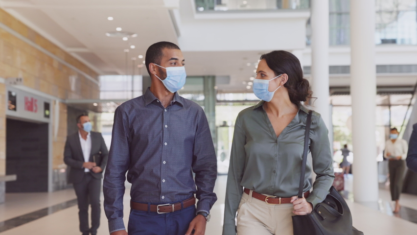 Indian business man and young businesswoman talking with face mask in the hallway of a business company. Business colleagues walking to the meeting while wearing protective face mask during covid19. Royalty-Free Stock Footage #1068792182