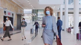 Mature businesswoman wearing protective face mask while walking to airport terminal, travel under Covid19 pandemic. Woman traveling for business during coronavirus outbreak going to boarding gate. - Powered by Shutterstock - Get 15% off with code: PIKWIZARD15