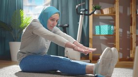 Beautiful young muslim woman in a national headscarf is warming up in front of a laptop
