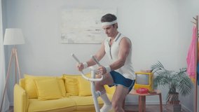 Sportsman training on exercise bike in living room, retro sport concept