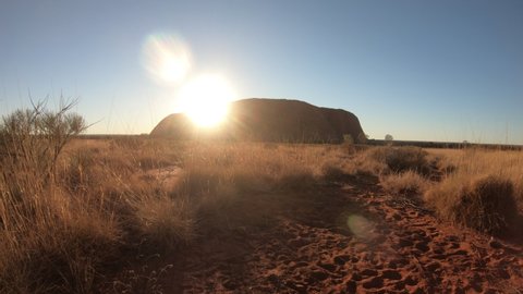 Australia - Aug 23, 2019:bush vegetation of Australian outback in dry season with iconic sandstone monolith at sunset called Uluru or Ayers Rock in Uluru - Kata Tjuta National Park, Northern Territory