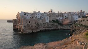 Polignano a Mare,Puglia,Bari,Italy.Beautiful 4K panoramic aerial video from flying drone to beach Lama Monachile,Polignano a Mare new and old city, Adriatic sea and Turquoise sea water at sunrise.