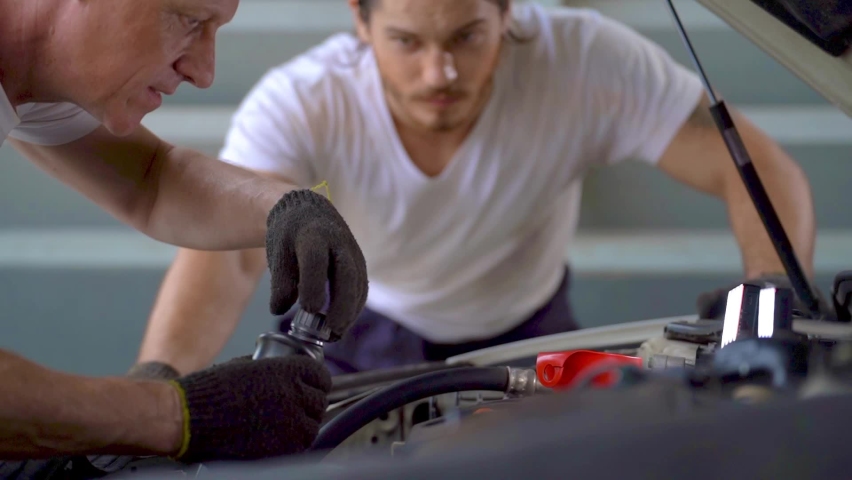 close up hand worker car service repairing and adding motor oil to engine at garage car parking. people working in industrial warehouse of spare parts transportation.