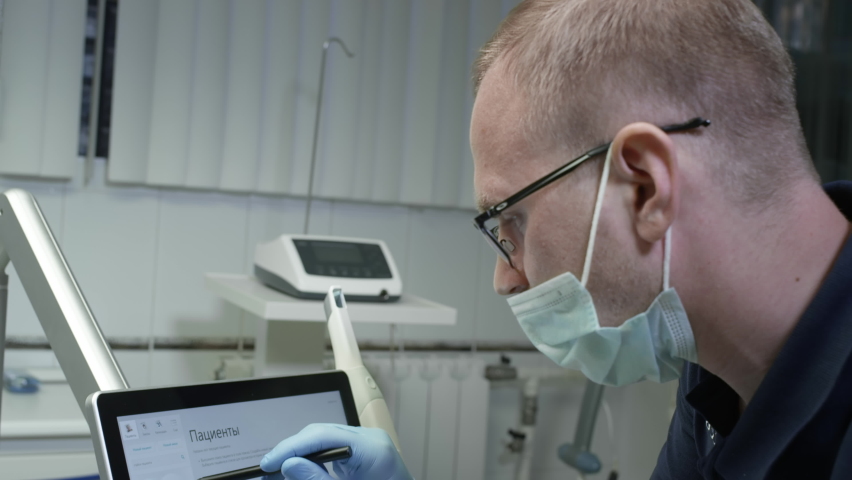 A professional dentist man looks at a 3d model of teeth on a computer monitor. Dental consultation, diagnostics. Jaw scan, digital imprint, medical digital technology. Royalty-Free Stock Footage #1068817688