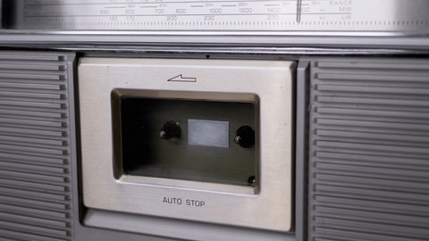 Open Cassette Deck of Old Tape Recorder, Insert 90s Cassette, Close with Fingers. Magnetic cassette tape inside player. Grey radio receiver in retro style with scale frequency range. Slow-motion. 4K.