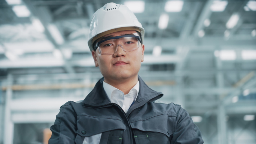 Portrait of a Professional Asian Heavy Industry Engineer Worker Wearing Safety Uniform, Glasses and Hard Hat. Confident Chinese Industrial Specialist Standing in a Factory Facility. Royalty-Free Stock Footage #1068840011