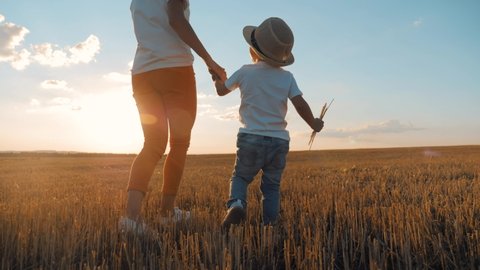 Happy family mom and son. Mother walks with little son holding hands at beautiful sunset. Mother holds her son by the hand. Helping hand. Teamwork and friendly family concept. Happy kid love for mom.