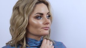 Beautiful young woman with bright evening make-up smoky eyes, freezes and wraps herself in a blue scarf. Girl model thoughtfully looks to the side on a white background. - Powered by Shutterstock - Get 15% off with code: PIKWIZARD15