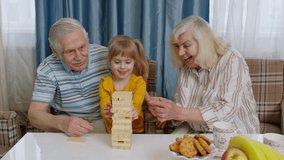 Excited little 5-6 years old cute child girl kid involved in funny build board game with smiling senior grandparents grandmother and grandfather. Building wooden tower and taking out blocks at home - Powered by Shutterstock - Get 15% off with code: PIKWIZARD15