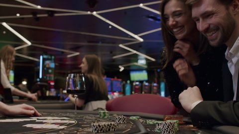 A young couple plays blackjack in an elite casino. The players are happy and celebrating a card win.. Gambling, nightlife