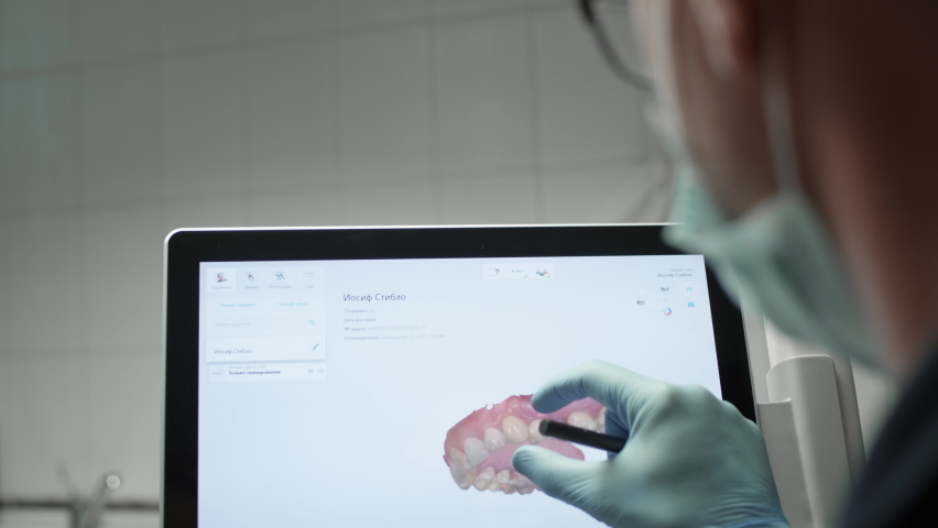 A professional dentist man looks at a 3d model of teeth on a computer monitor. Dental consultation, diagnostics. Jaw scan, digital imprint, medical digital technology. Royalty-Free Stock Footage #1068847172