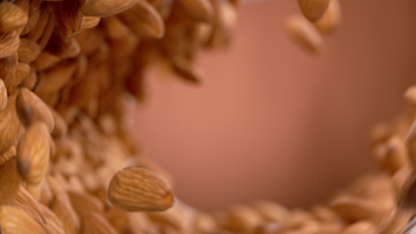 Super Slow Motion Shot of Almonds Making Vortex Shape on Brown Gradient Background at 1000 fps. Royalty-Free Stock Footage #1068851072