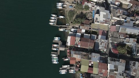 Birds eye view of Boats docked on Lake shoreline drone panning forwards during afternoon over houses