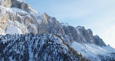 Mountain Aerial Landscape, flying over Hills and Forests covered in Snow after Snow fall in the Alps. Sella Mountain Rock face. Wilderness in Italy in Dolomites UNESCO World Heritage