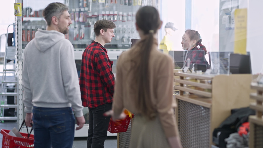 Queue arguing with buyer standing at cashier in hardware store. Irritated Caucasian men and woman shouting and gesturing buying tools and supplies in shop indoors. Conflict and consumerism.