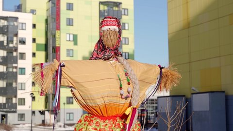 Maslenitsa. winter scarecrow from hay before burning in traditional Russian dress in the courtyard of a multi-storey building close-up