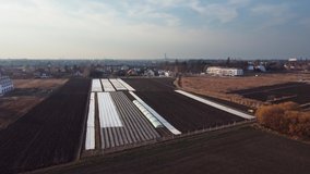 Aerial drone video of plowed spring field covered polyethylene. Agriculture and farming. Fly over field with small greenhouses. 4K drone footage. Top view. - Powered by Shutterstock - Get 15% off with code: PIKWIZARD15