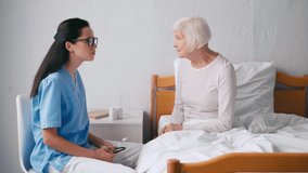 brunette doctor talking to aged woman in hospital