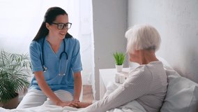 young positive geriatrician talking to aged woman in hospital
